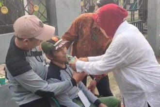 Calon Gubernur Jawa Timur Tri Rismaharini membantu petugas linmas yang sempat pingsan saat bertugas menjaga TPS di Jajar Tunggal, Wiyung, Surabaya. (Foto : kfp)