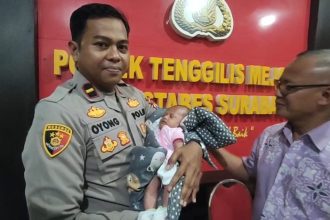 Kanit Reskrim Polsek Tenggilis Mejoyo, Surabaya, IPDA Oyong menggendong bayi yang dibuang. (foto : kfp)
