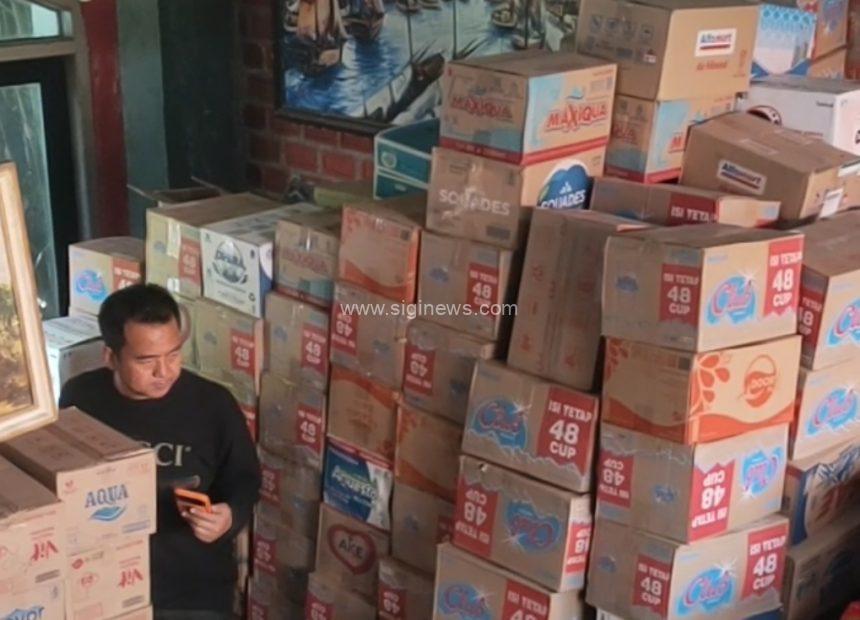 Cak Sholeh berada di tengah tumpukan duz air mineral dalam kemasan hasil donasi masyarakat. (foto: jero)